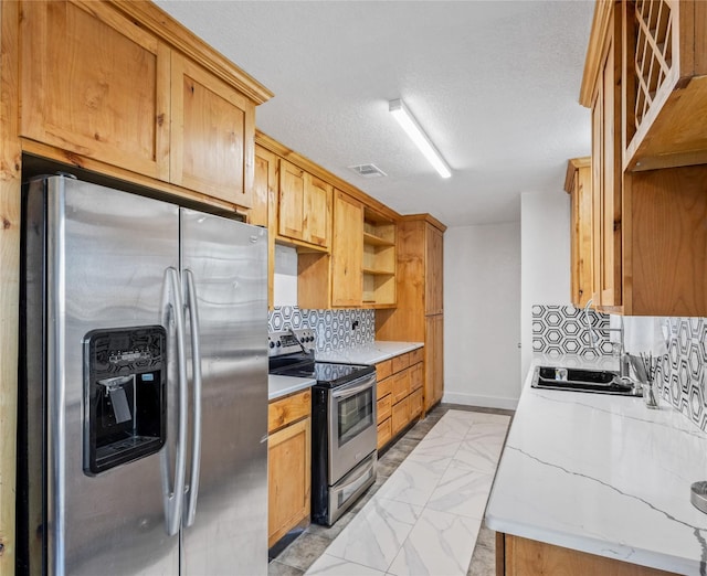 kitchen featuring decorative backsplash, a textured ceiling, stainless steel appliances, and sink