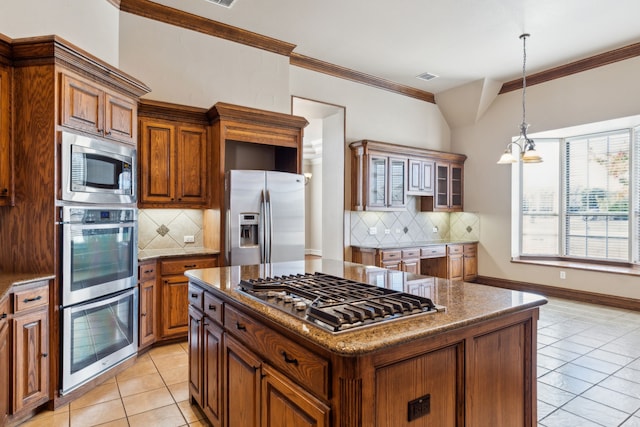 kitchen featuring light tile patterned floors, tasteful backsplash, a chandelier, a kitchen island, and appliances with stainless steel finishes