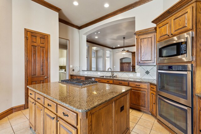 kitchen with stone counters, sink, stainless steel appliances, light tile patterned floors, and a kitchen island