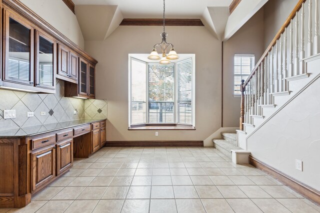 kitchen with ornamental molding, backsplash, decorative light fixtures, and a notable chandelier