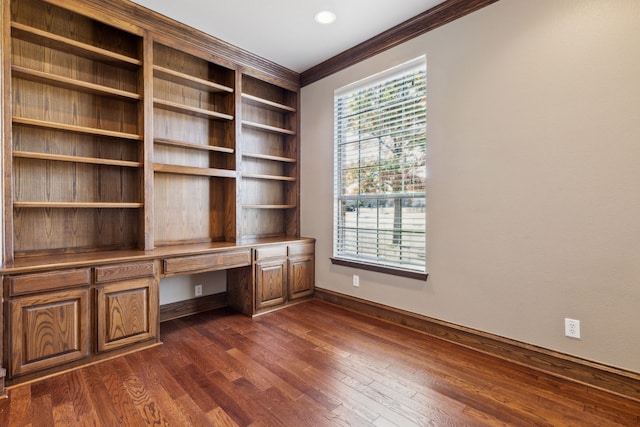 unfurnished office with built in desk, dark hardwood / wood-style floors, and crown molding