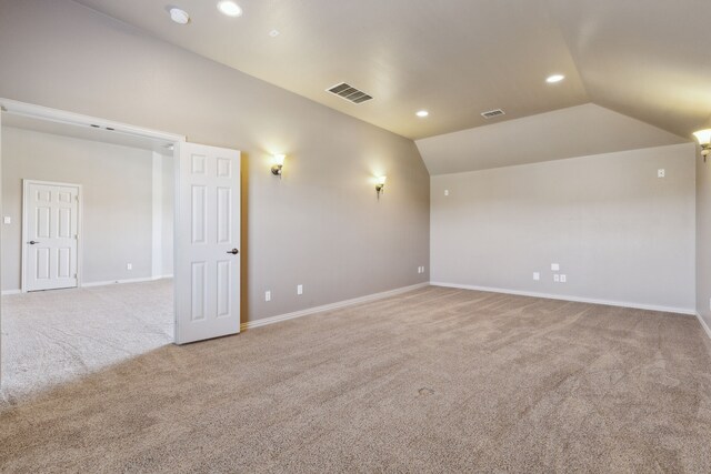 spare room with light colored carpet and lofted ceiling