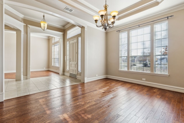 foyer featuring a chandelier, wood-type flooring, crown molding, and a healthy amount of sunlight