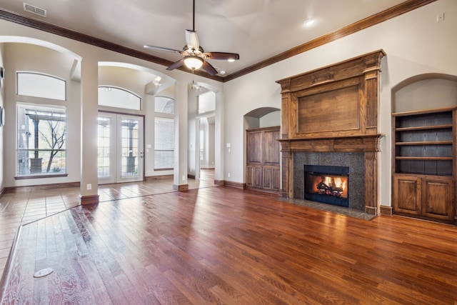 unfurnished living room featuring ceiling fan, crown molding, dark wood-type flooring, and a tile fireplace