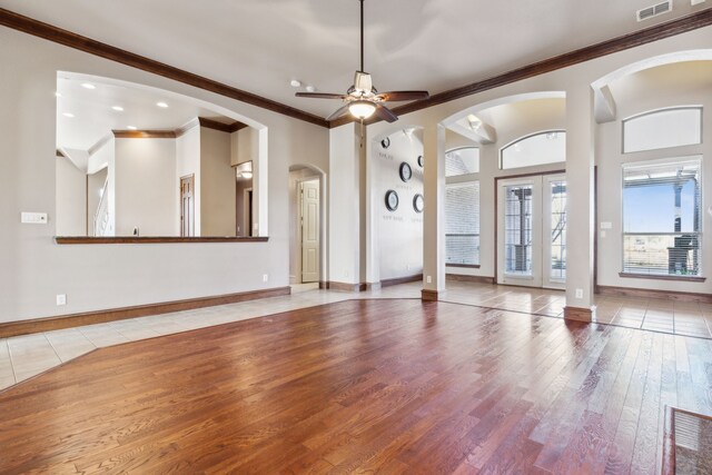 unfurnished living room featuring hardwood / wood-style flooring, ceiling fan, ornamental molding, and french doors