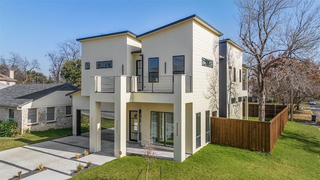 back of house featuring a balcony, a patio area, and a lawn