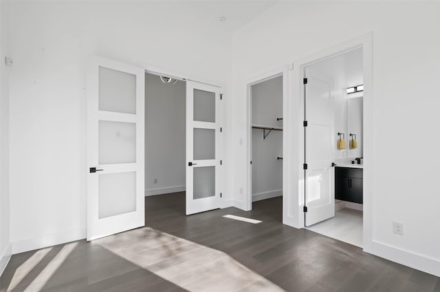 unfurnished bedroom featuring hardwood / wood-style flooring, a closet, a spacious closet, and ensuite bath