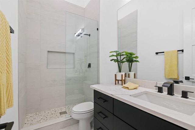 bathroom featuring vanity, toilet, and tiled shower