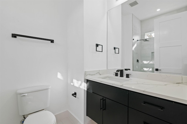 bathroom with tiled shower, vanity, and toilet