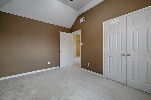 unfurnished bedroom featuring light colored carpet, high vaulted ceiling, and a closet