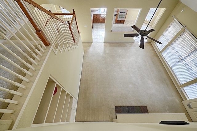 staircase featuring ceiling fan and a high ceiling