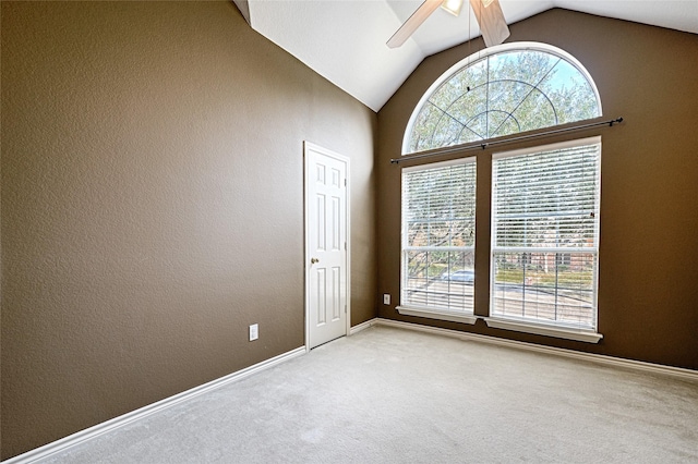 carpeted spare room with ceiling fan, high vaulted ceiling, and a healthy amount of sunlight