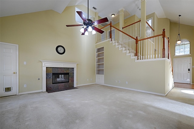 unfurnished living room featuring a tile fireplace, ceiling fan, high vaulted ceiling, and light colored carpet