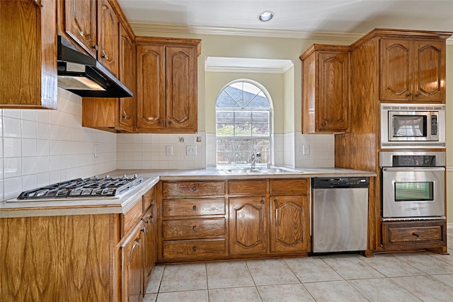 kitchen featuring tasteful backsplash, stainless steel appliances, crown molding, sink, and light tile patterned flooring