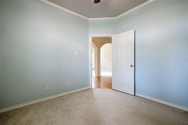 empty room with crown molding, ceiling fan, and light colored carpet