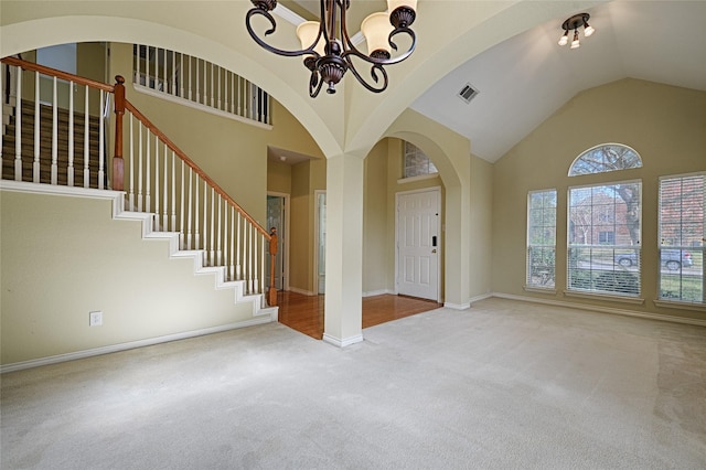 carpeted foyer featuring an inviting chandelier and high vaulted ceiling