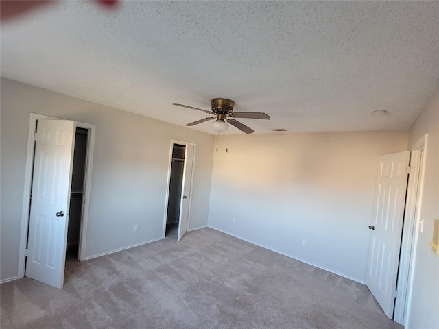 unfurnished bedroom featuring light carpet, a textured ceiling, and ceiling fan