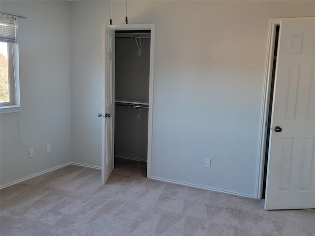 unfurnished bedroom featuring a closet and light colored carpet