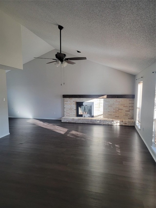 unfurnished living room with a brick fireplace, dark hardwood / wood-style flooring, a textured ceiling, and vaulted ceiling