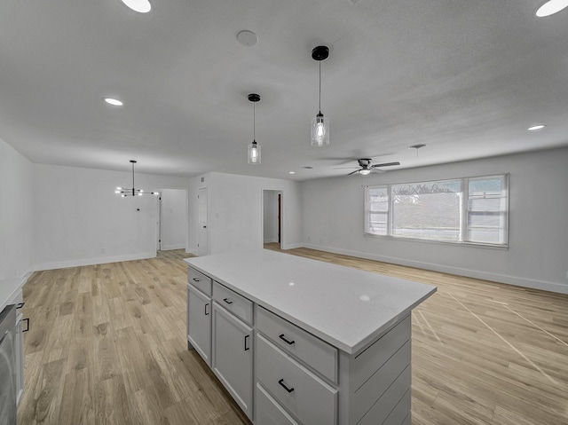 kitchen featuring a kitchen island, decorative light fixtures, white cabinets, ceiling fan with notable chandelier, and light wood-type flooring