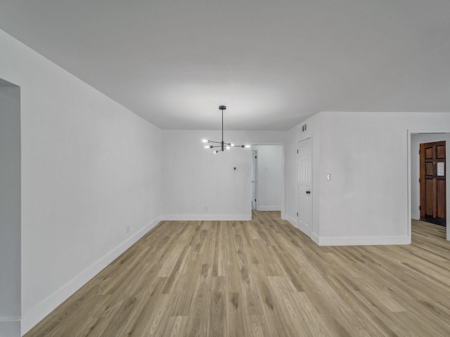 unfurnished room featuring light hardwood / wood-style flooring and a notable chandelier