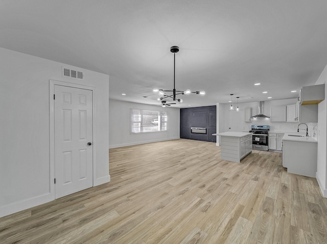 unfurnished living room featuring light wood-type flooring, a notable chandelier, and sink