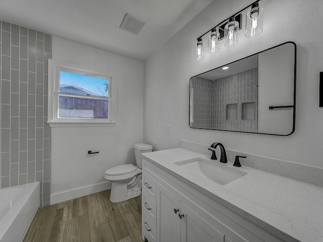 full bathroom with vanity, wood-type flooring, tiled shower / bath combo, and toilet