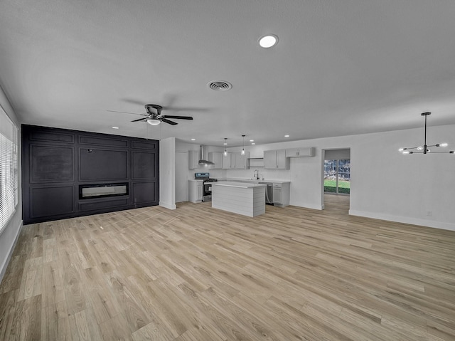 unfurnished living room with sink, light hardwood / wood-style floors, and ceiling fan with notable chandelier