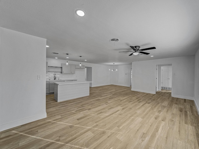 unfurnished living room with ceiling fan, light wood-type flooring, and sink