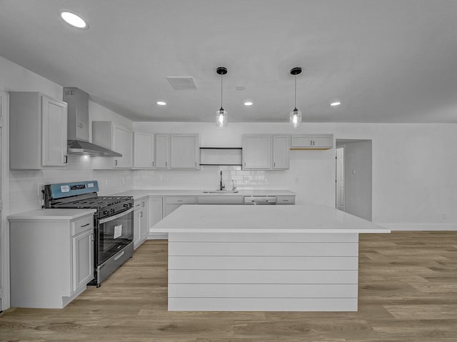 kitchen with a center island, sink, light hardwood / wood-style flooring, wall chimney exhaust hood, and stainless steel appliances