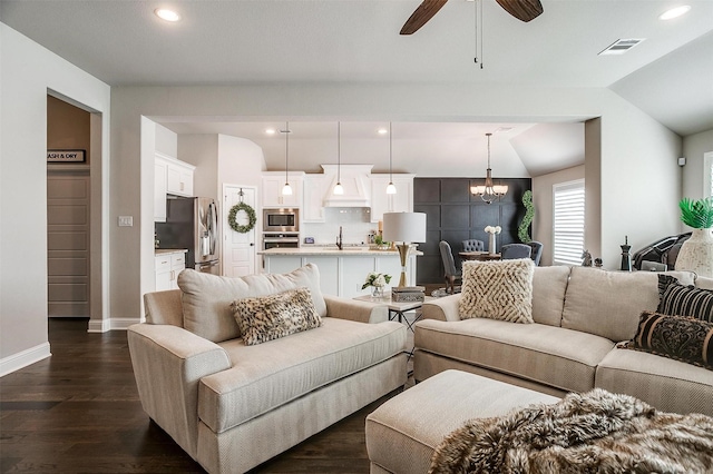 living room featuring ceiling fan with notable chandelier, dark hardwood / wood-style floors, vaulted ceiling, and sink