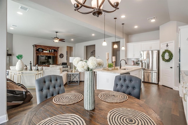 dining area featuring sink, ceiling fan with notable chandelier, and dark hardwood / wood-style floors