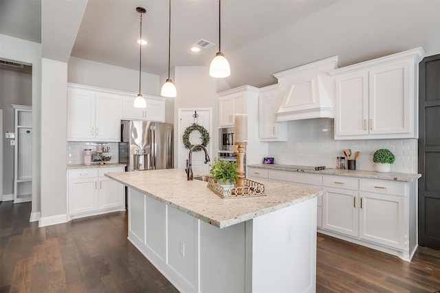 kitchen featuring stainless steel appliances, dark hardwood / wood-style floors, decorative light fixtures, a center island with sink, and white cabinets