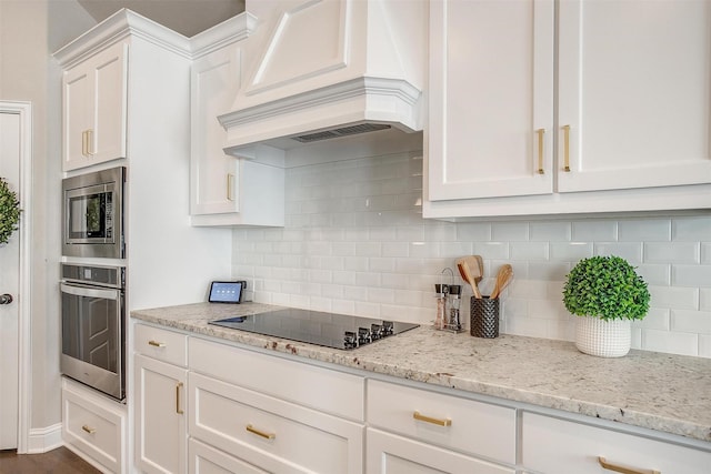 kitchen with white cabinetry, light stone countertops, backsplash, black electric cooktop, and custom range hood