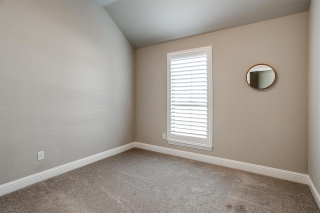 carpeted spare room with vaulted ceiling