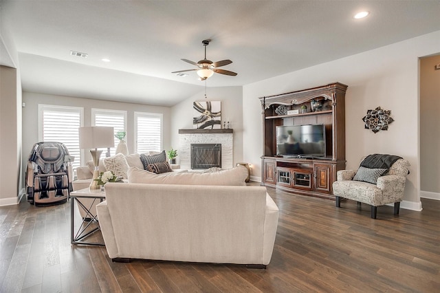 living room featuring dark wood-type flooring, a stone fireplace, ceiling fan, and lofted ceiling