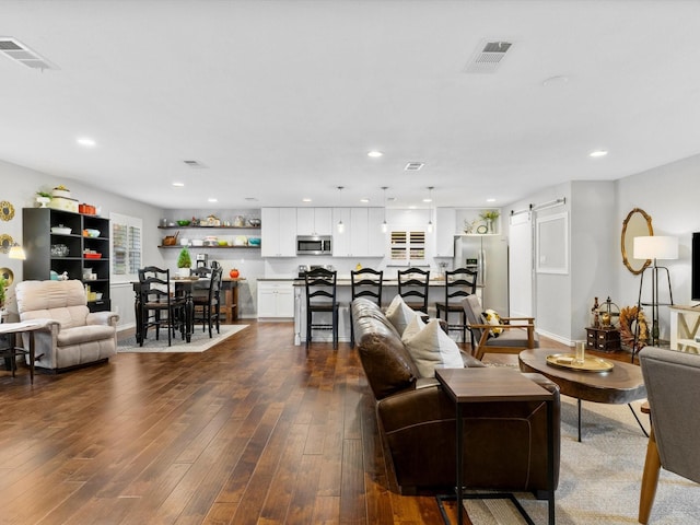 living room featuring a barn door and dark hardwood / wood-style flooring