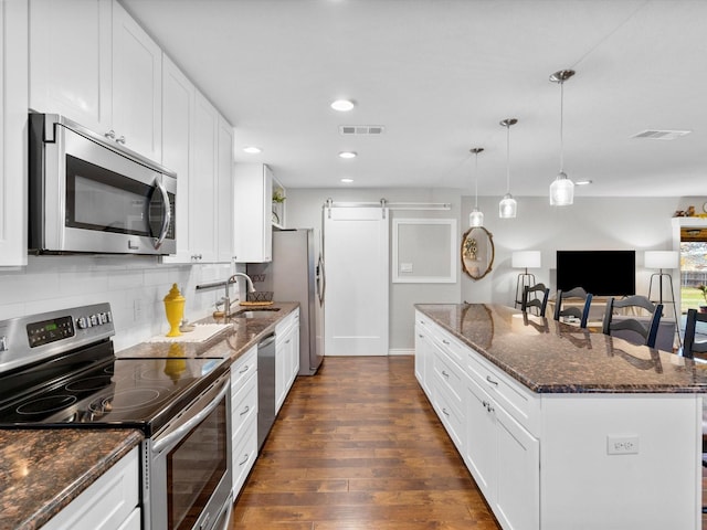 kitchen with white cabinetry, sink, a barn door, dark hardwood / wood-style flooring, and appliances with stainless steel finishes