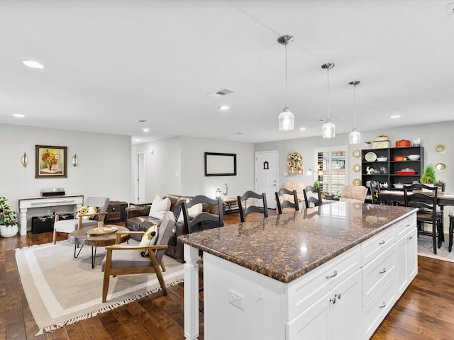 kitchen featuring hanging light fixtures, a kitchen island, dark stone countertops, and white cabinets