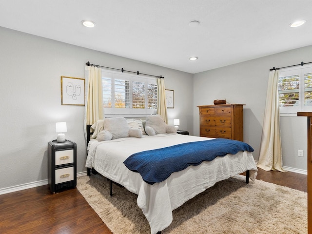 bedroom with multiple windows and dark hardwood / wood-style floors