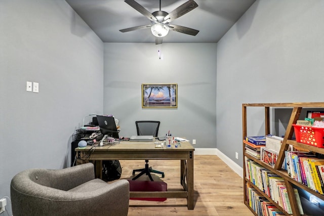 home office with light hardwood / wood-style floors and ceiling fan