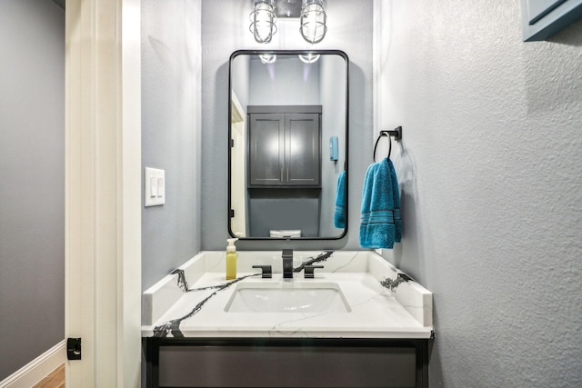 bathroom featuring a textured wall, vanity, and baseboards