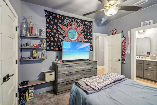 carpeted bedroom with ensuite bath, visible vents, ceiling fan, and baseboards