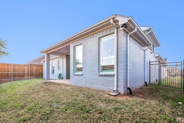 back of property with brick siding, a lawn, and fence