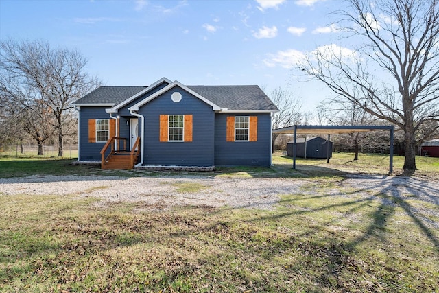 view of front of home with a carport, a front yard, and a storage shed