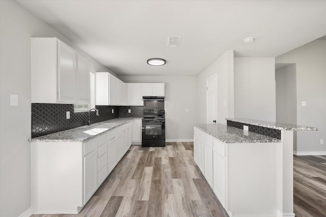 kitchen featuring sink, white cabinetry, electric range, a center island, and light stone countertops