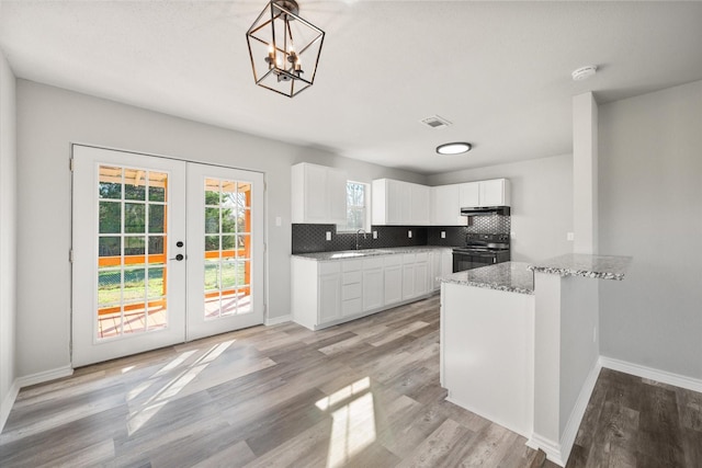 kitchen featuring black electric range oven, sink, decorative light fixtures, kitchen peninsula, and white cabinets