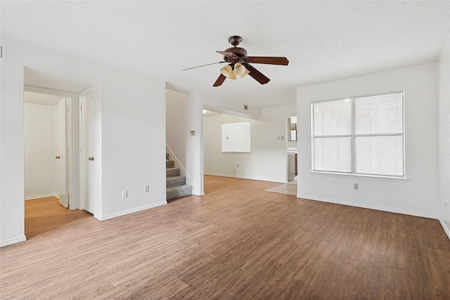 unfurnished living room with ceiling fan, light hardwood / wood-style floors, and a textured ceiling