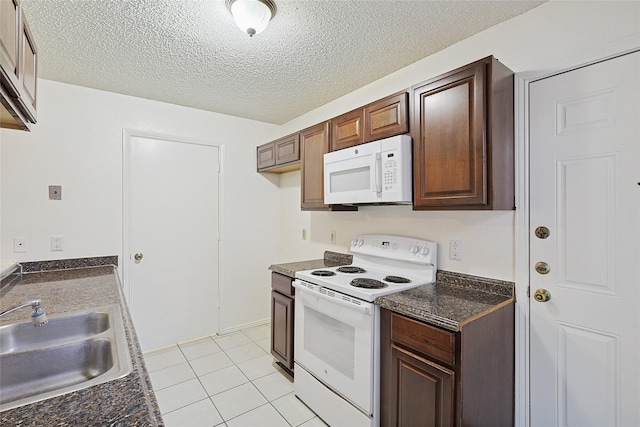 kitchen with light tile patterned floors, white appliances, a textured ceiling, and sink