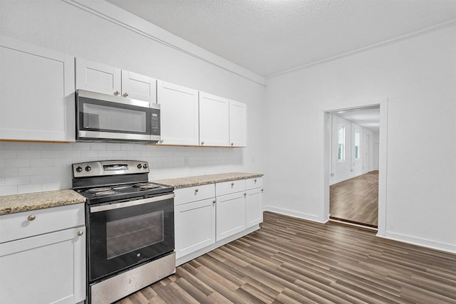 kitchen with decorative backsplash, dark hardwood / wood-style flooring, a textured ceiling, stainless steel appliances, and white cabinetry